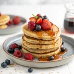 Fluffy protein pancakes without protein powder topped with fresh berries and drizzled maple syrup.