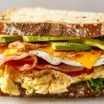 Ultimate protein breakfast sandwich with eggs, turkey bacon, cheese and avocado on artisan bread