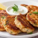 Golden crispy salmon patties served with fresh herbs and lemon slices