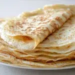 Thin sourdough discard crepes folded and served with fresh berries and powdered sugar